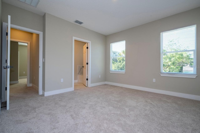 unfurnished bedroom with ensuite bathroom and light carpet