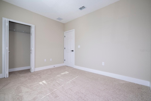 unfurnished bedroom featuring light carpet and a closet