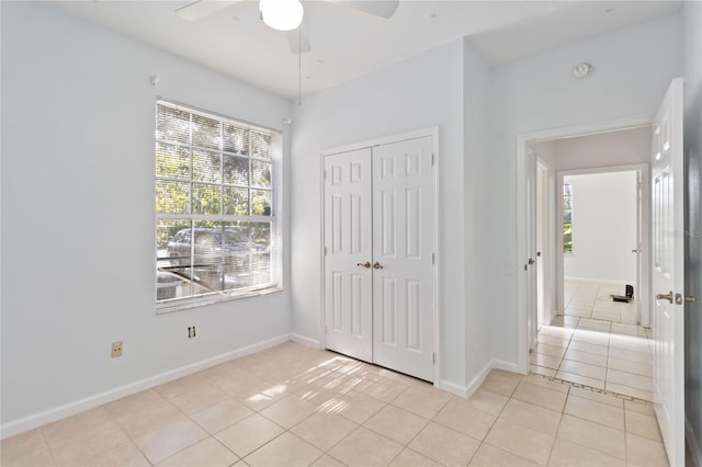 unfurnished bedroom with ceiling fan, light tile patterned floors, and a closet