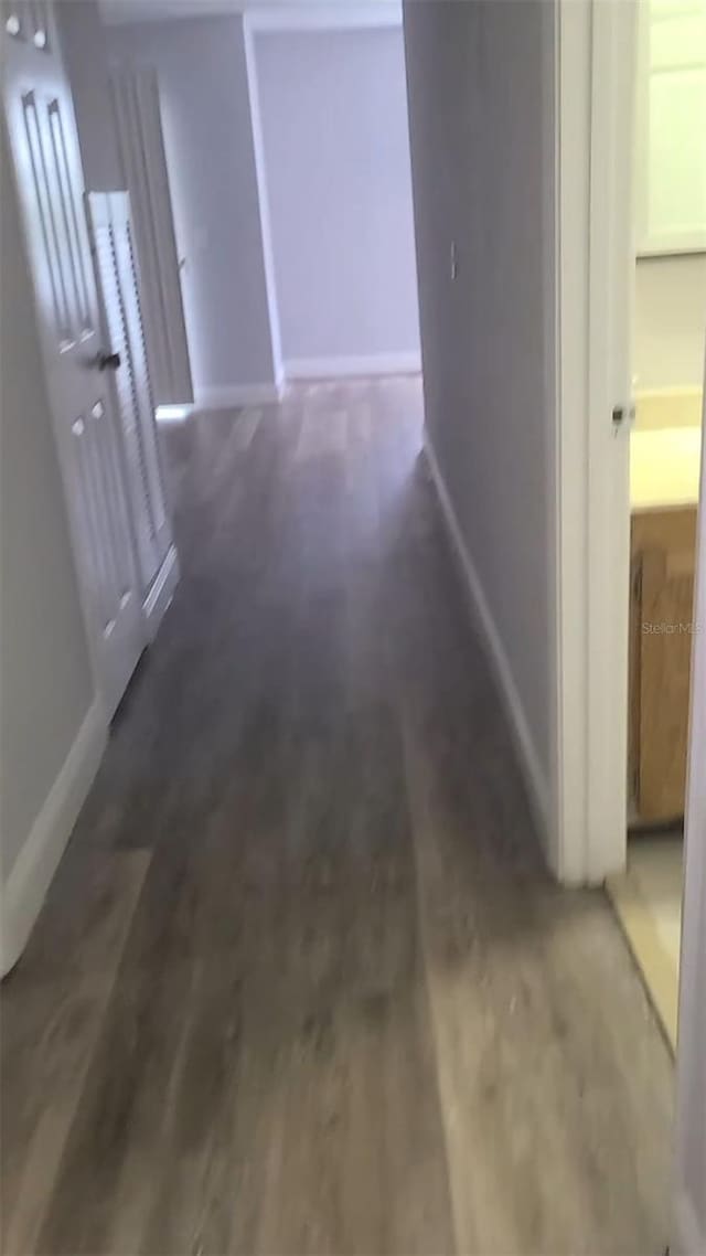 hallway featuring baseboards and wood finished floors