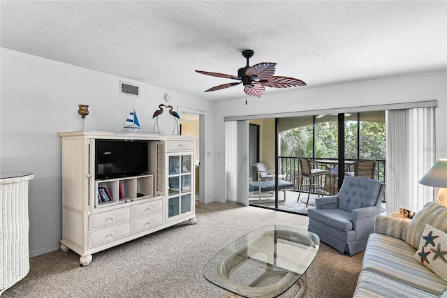 living room with ceiling fan, carpet floors, and a textured ceiling