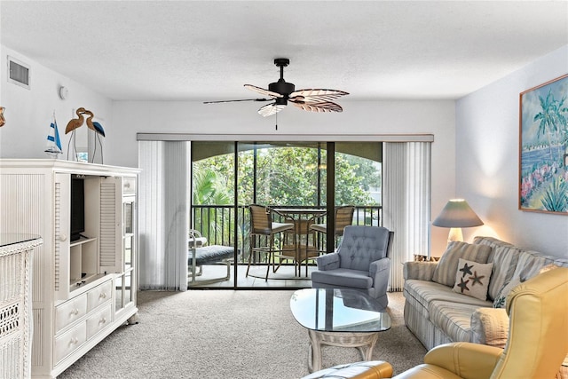 carpeted living room with a textured ceiling and ceiling fan