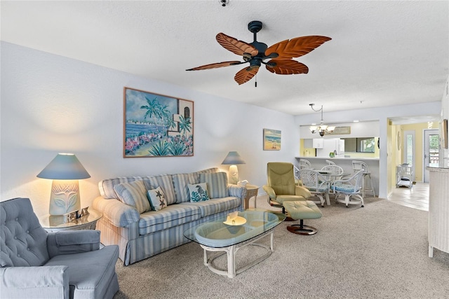 living room with carpet, ceiling fan with notable chandelier, and a textured ceiling