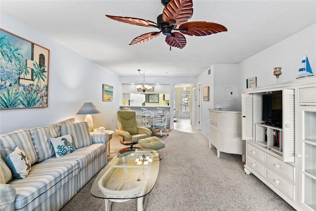 carpeted living room with a textured ceiling and ceiling fan with notable chandelier