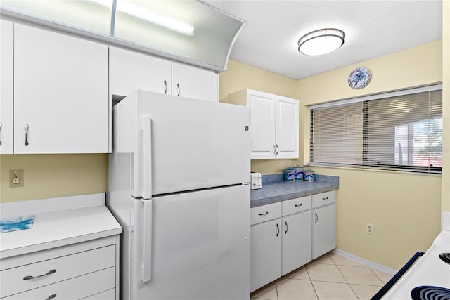 kitchen featuring white cabinets, light tile patterned floors, and white fridge