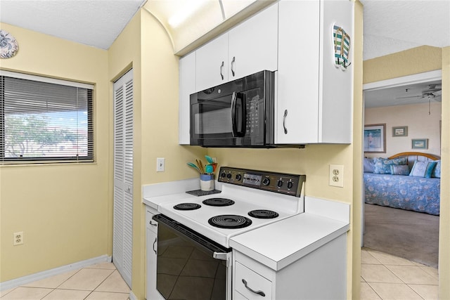 kitchen featuring white electric range, light tile patterned floors, a textured ceiling, and white cabinetry