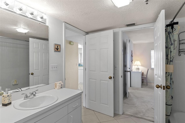 bathroom with tile patterned flooring, vanity, a textured ceiling, and tiled shower / bath