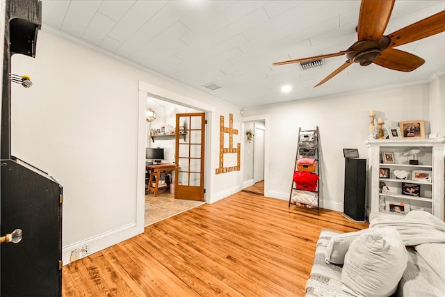 living room featuring ceiling fan, ornamental molding, and light wood-type flooring