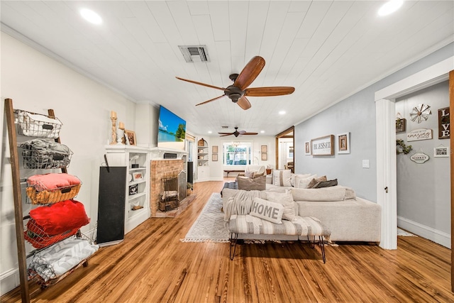 living room featuring crown molding, wooden ceiling, a fireplace, and light hardwood / wood-style floors