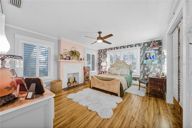 bedroom with hardwood / wood-style flooring, ceiling fan, and crown molding