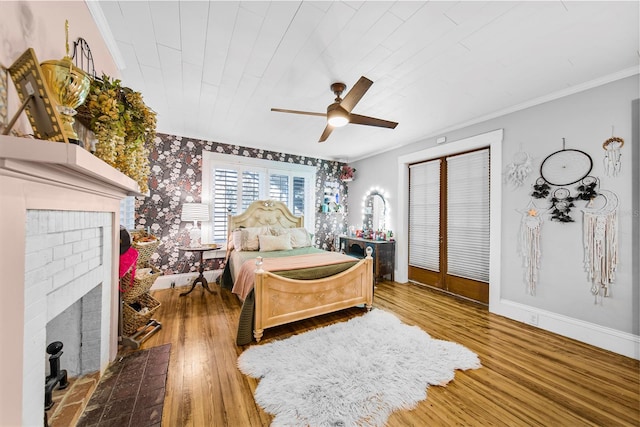 bedroom featuring wooden ceiling, ornamental molding, hardwood / wood-style flooring, ceiling fan, and a fireplace