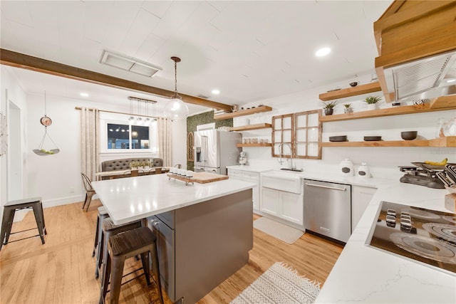 kitchen featuring appliances with stainless steel finishes, sink, a breakfast bar area, white cabinets, and hanging light fixtures