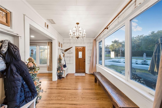 entryway with ornamental molding, light hardwood / wood-style flooring, and a notable chandelier