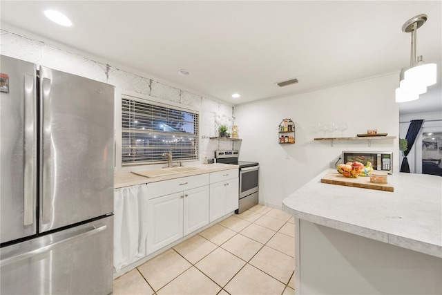 kitchen with light tile patterned floors, sink, white cabinetry, hanging light fixtures, and stainless steel appliances