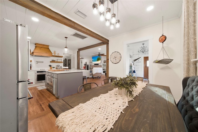 dining room with crown molding, ceiling fan, wood-type flooring, and beam ceiling