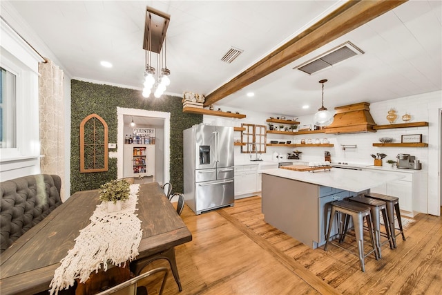 kitchen with a kitchen island, pendant lighting, high end refrigerator, white cabinets, and custom exhaust hood