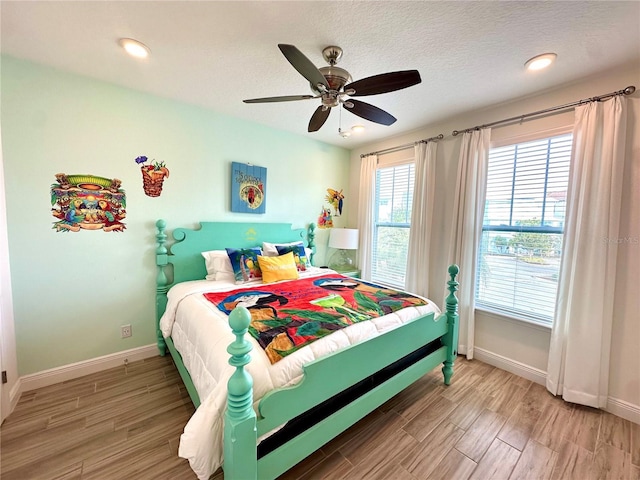 bedroom with ceiling fan, hardwood / wood-style floors, and a textured ceiling