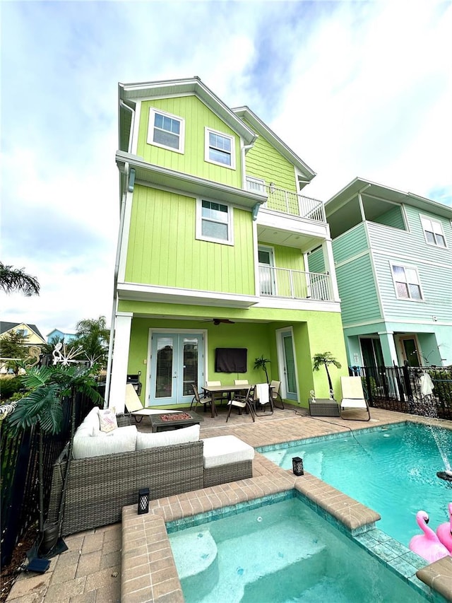 rear view of house with outdoor lounge area, a fenced in pool, french doors, a balcony, and a patio area