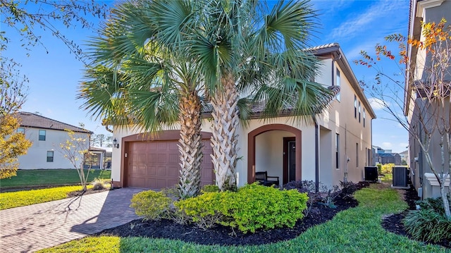 mediterranean / spanish house featuring a garage, central AC unit, and a front yard