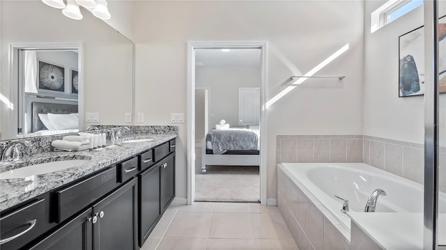 bathroom with tiled tub, tile patterned flooring, and vanity