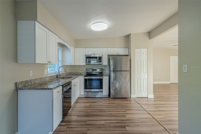 kitchen with white cabinets, sink, light hardwood / wood-style flooring, vaulted ceiling, and stainless steel appliances