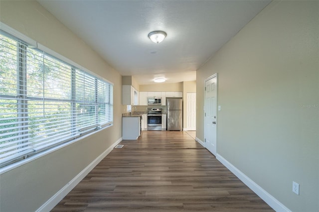 hallway with a healthy amount of sunlight, sink, lofted ceiling, and dark wood-type flooring