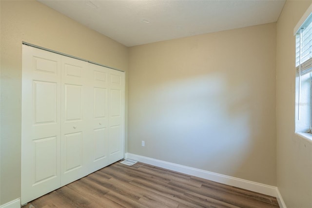 unfurnished bedroom featuring a closet and hardwood / wood-style floors