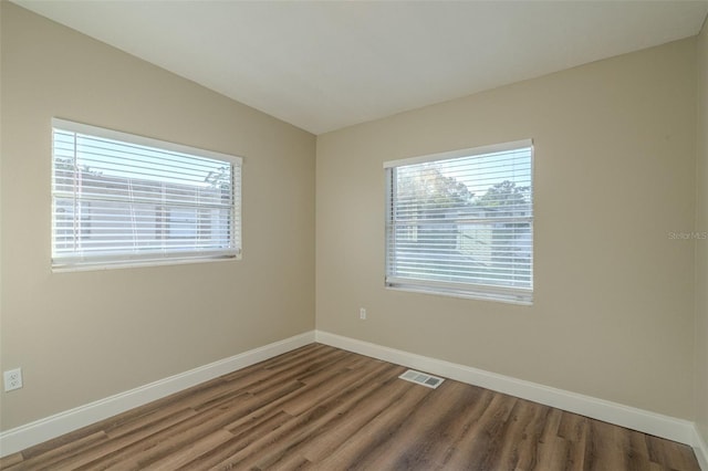 spare room with hardwood / wood-style flooring and vaulted ceiling