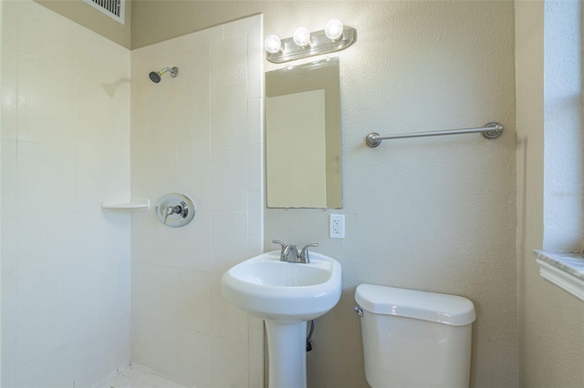 bathroom with tiled shower and toilet