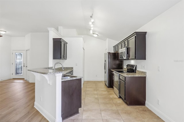 kitchen featuring sink, stainless steel appliances, light stone counters, a kitchen bar, and light wood-type flooring