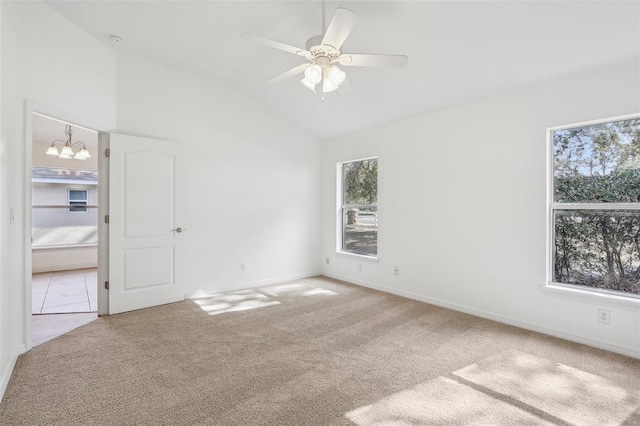 carpeted empty room featuring ceiling fan with notable chandelier, lofted ceiling, and a healthy amount of sunlight