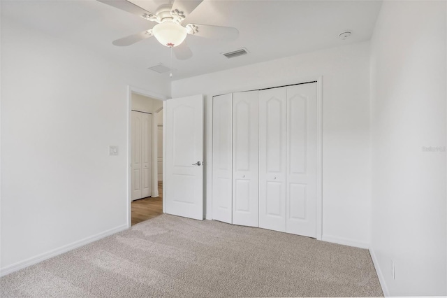 unfurnished bedroom with ceiling fan, light carpet, and a closet