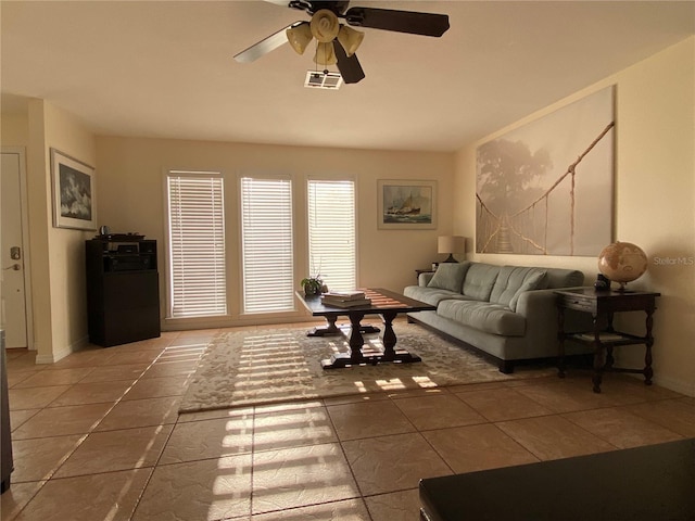 living room with ceiling fan and dark tile patterned floors