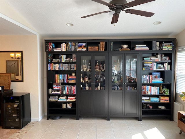 interior space with wine cooler, ceiling fan, light tile patterned floors, and a textured ceiling