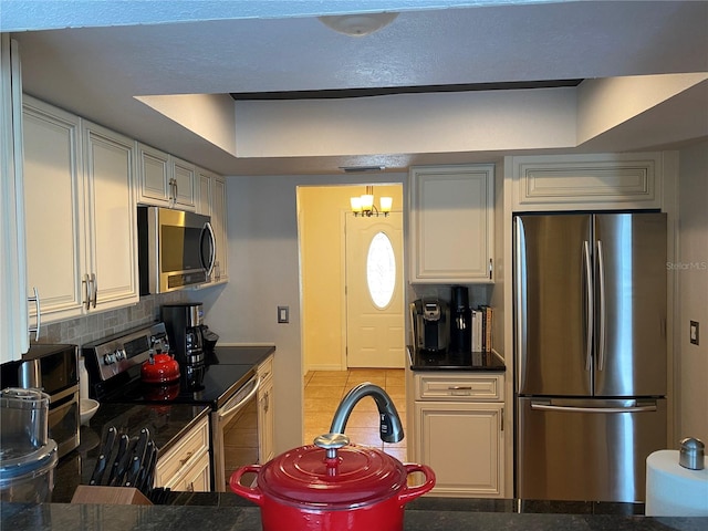 kitchen featuring backsplash, an inviting chandelier, light tile patterned flooring, and appliances with stainless steel finishes