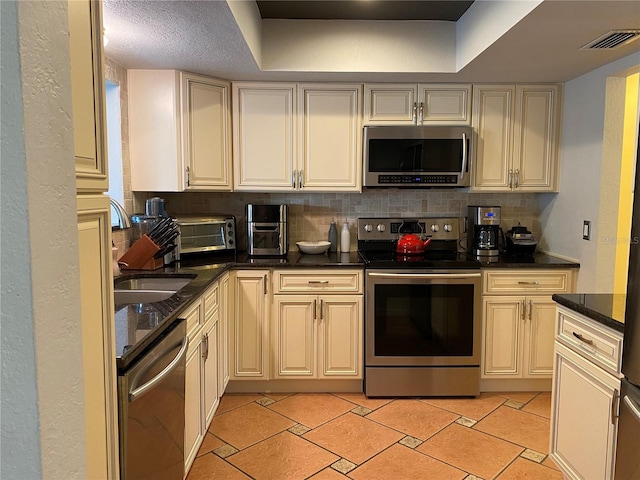 kitchen featuring backsplash, a raised ceiling, sink, and stainless steel appliances