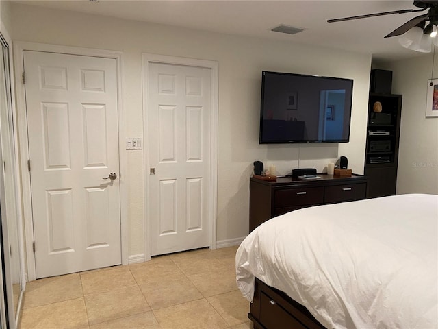 tiled bedroom featuring ceiling fan and two closets