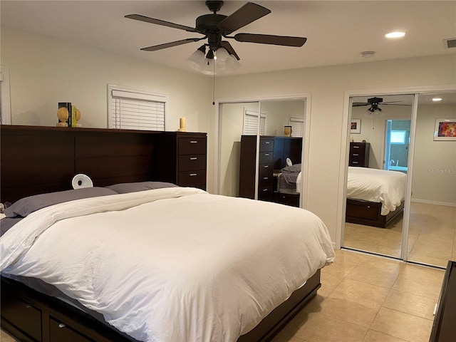 bedroom with ceiling fan, light tile patterned floors, and two closets