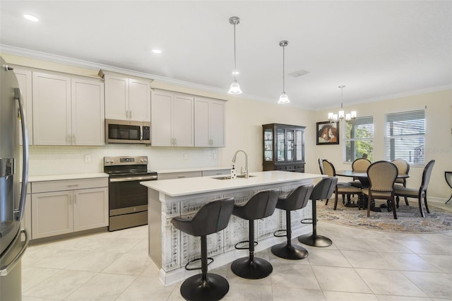 kitchen with an inviting chandelier, sink, an island with sink, appliances with stainless steel finishes, and decorative light fixtures