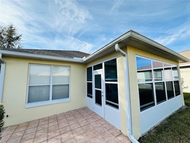 view of property exterior with a patio and a sunroom