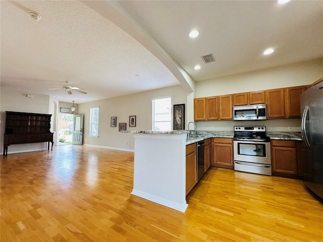 kitchen featuring kitchen peninsula, plenty of natural light, light wood-type flooring, and appliances with stainless steel finishes