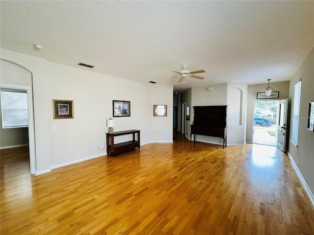 unfurnished living room featuring ceiling fan, light hardwood / wood-style flooring, and a textured ceiling