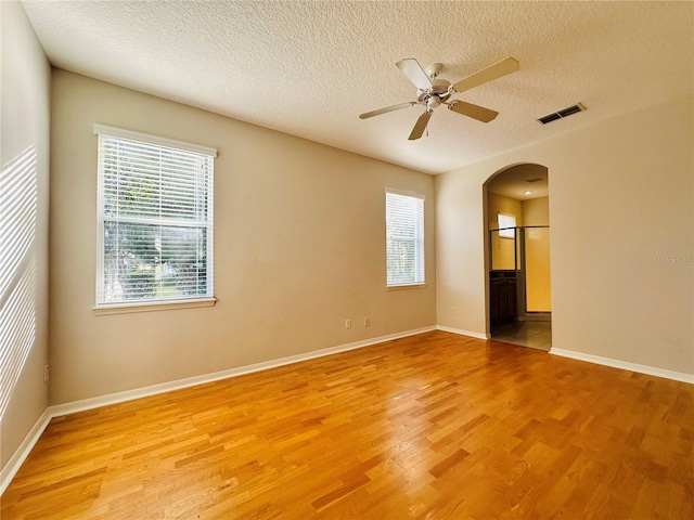 empty room with plenty of natural light, light hardwood / wood-style floors, and a textured ceiling