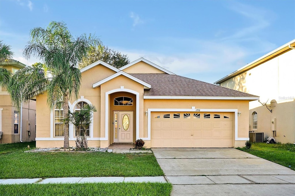 view of front of house featuring cooling unit, a front lawn, and a garage