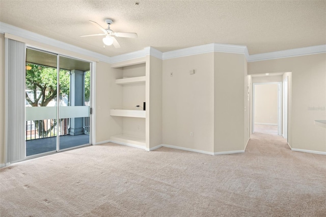 spare room featuring a textured ceiling, light colored carpet, ceiling fan, and crown molding