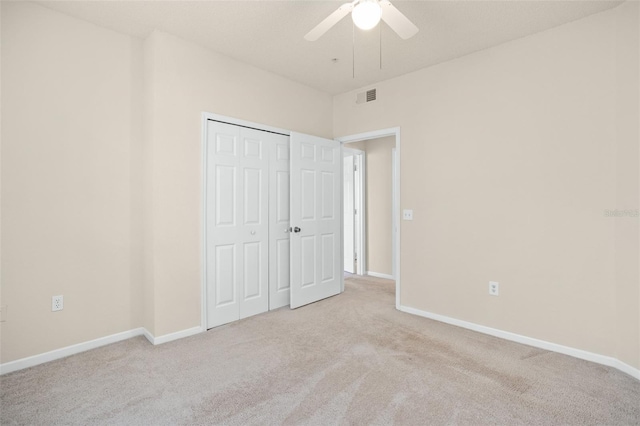 unfurnished bedroom with ceiling fan, light carpet, and a closet