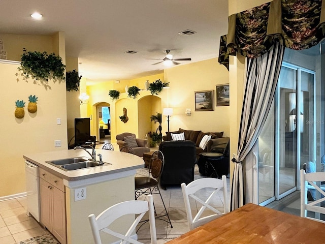 kitchen with light brown cabinetry, ceiling fan, sink, a center island with sink, and dishwasher