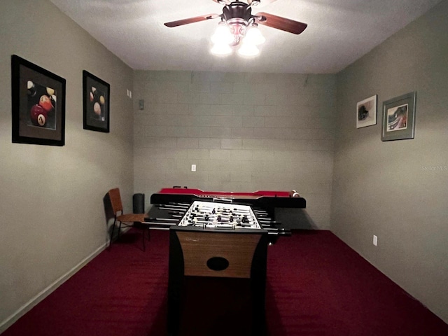 game room with ceiling fan and dark colored carpet