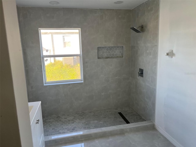 bathroom with tiled shower and vanity