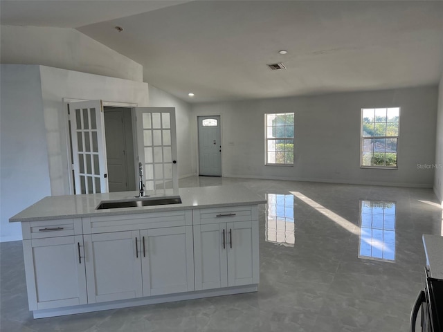 kitchen with a center island, lofted ceiling, french doors, white cabinets, and sink